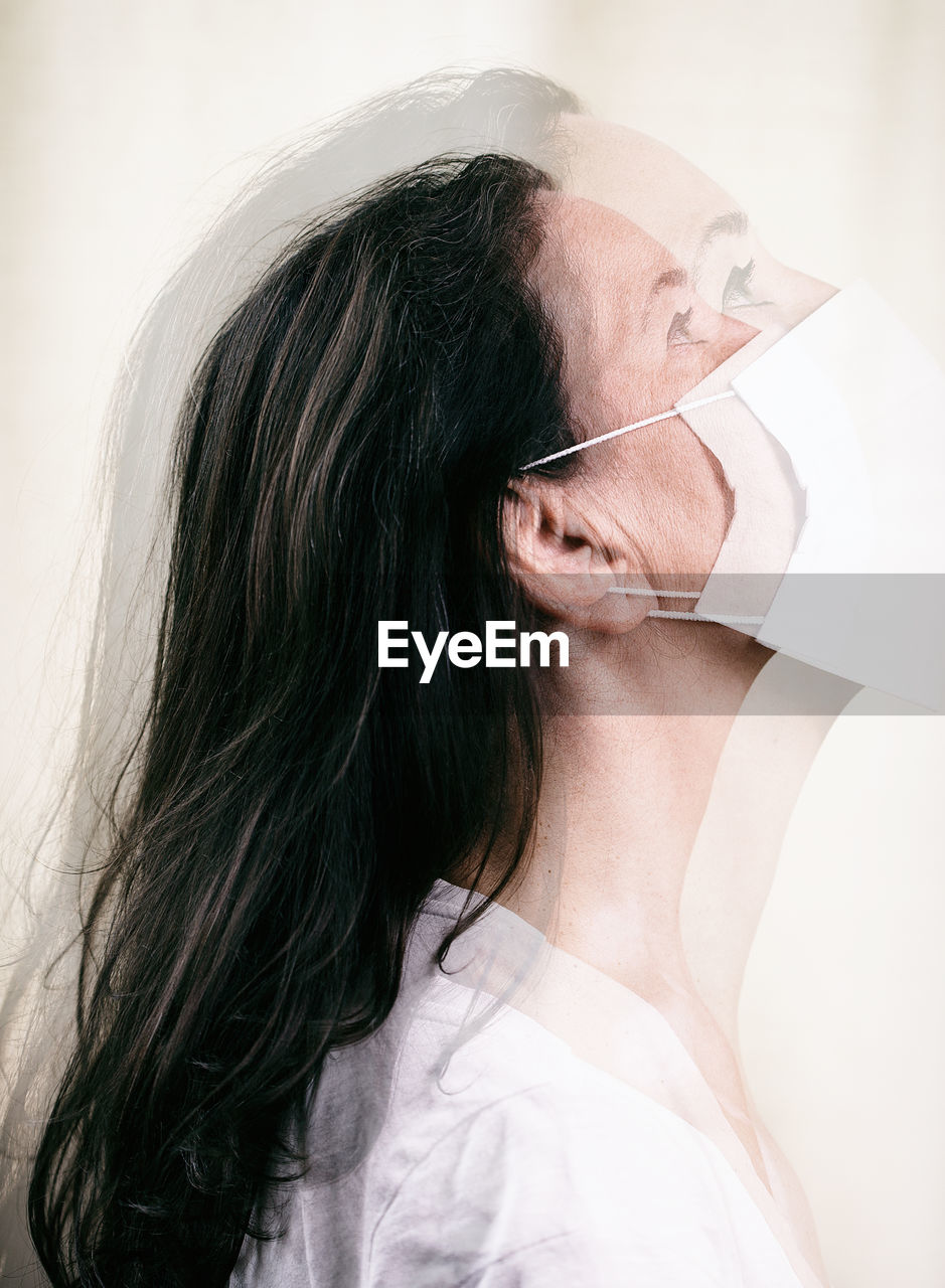 Multiple exposure image of woman wearing mask looking away against white background