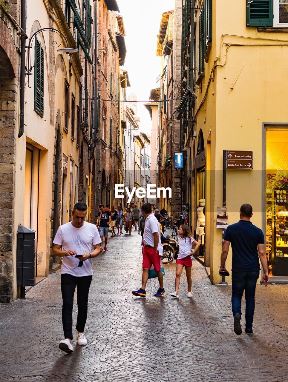 PEOPLE WALKING ON STREET AMIDST BUILDINGS