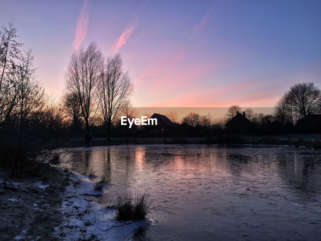 Scenic view of lake and silhouette trees at dusk during winter