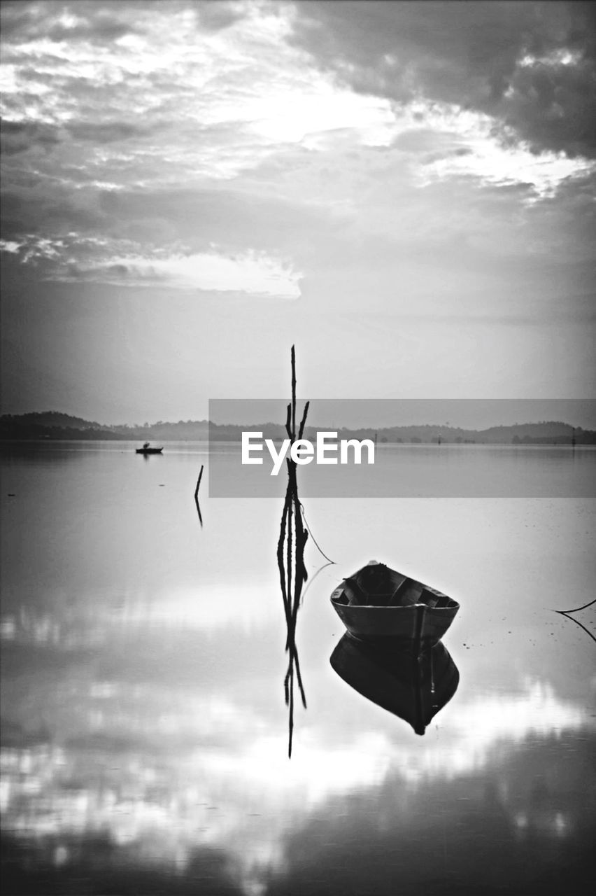 Empty wooden boat moored on river against sky