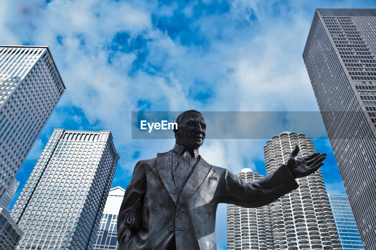 Statue of man in suit against skyscrapers