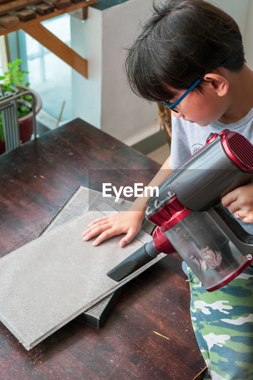 High angle view of boy cleaning on table