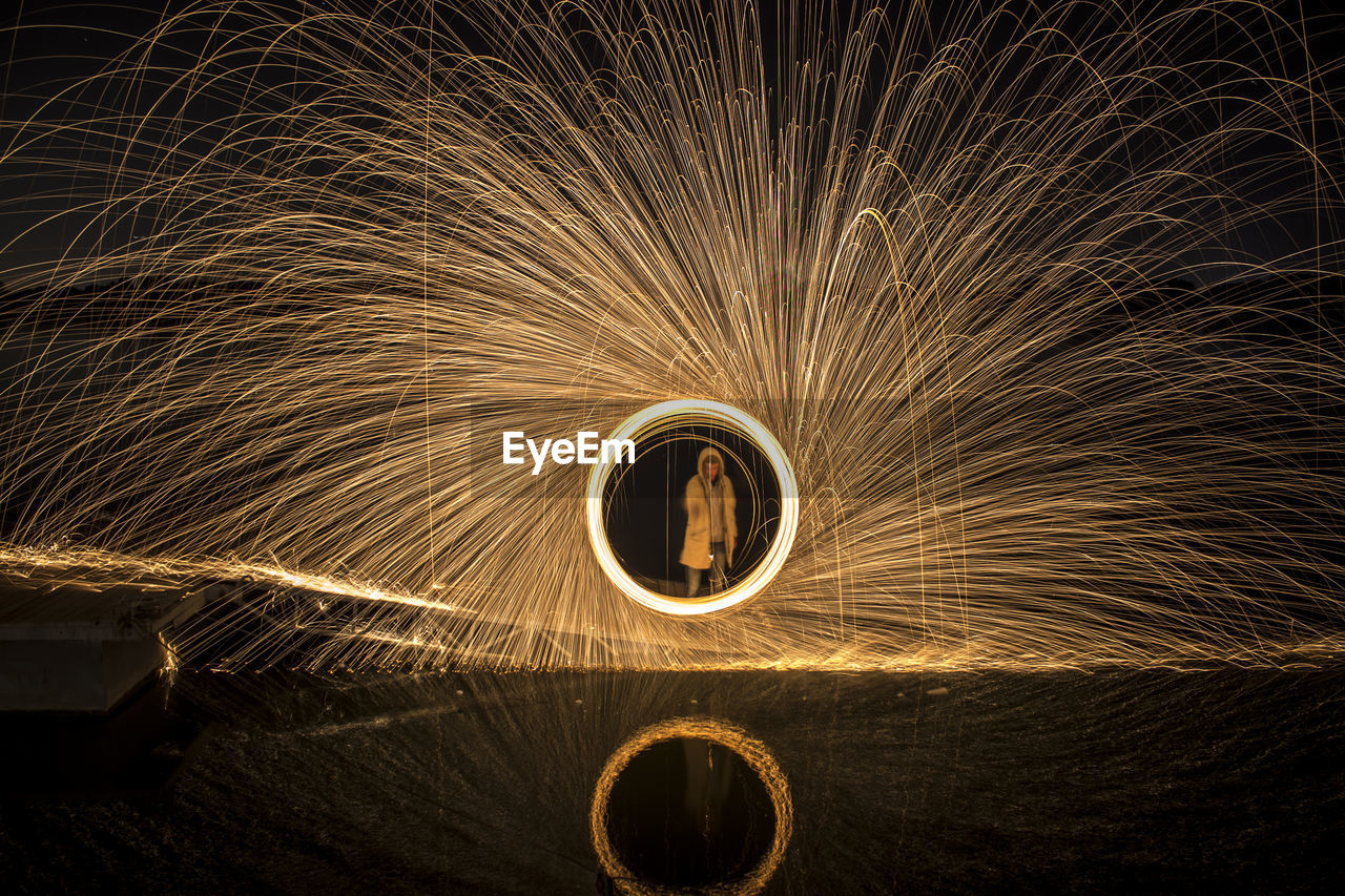 Man standing amidst wire wool at night