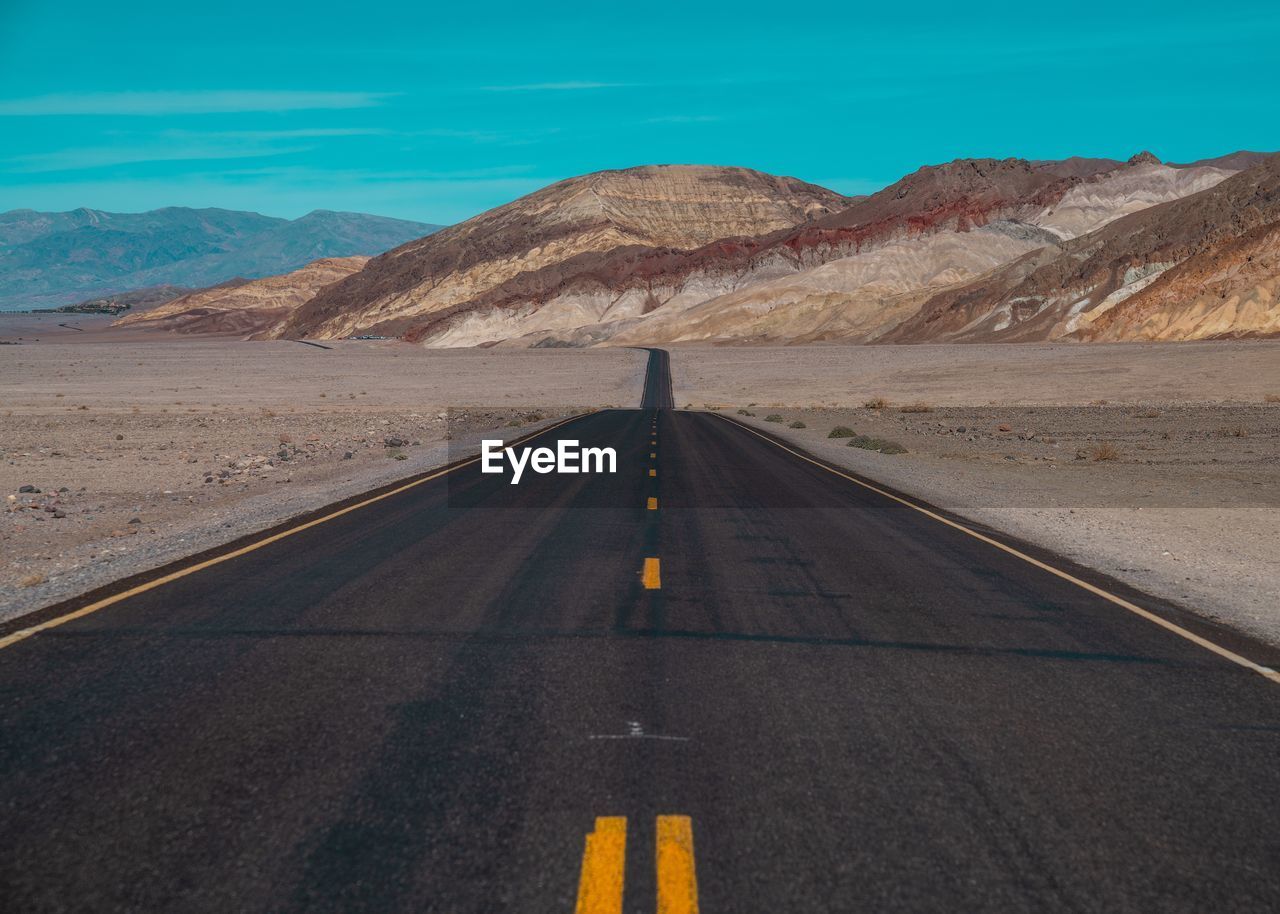 Road leading towards mountains against sky