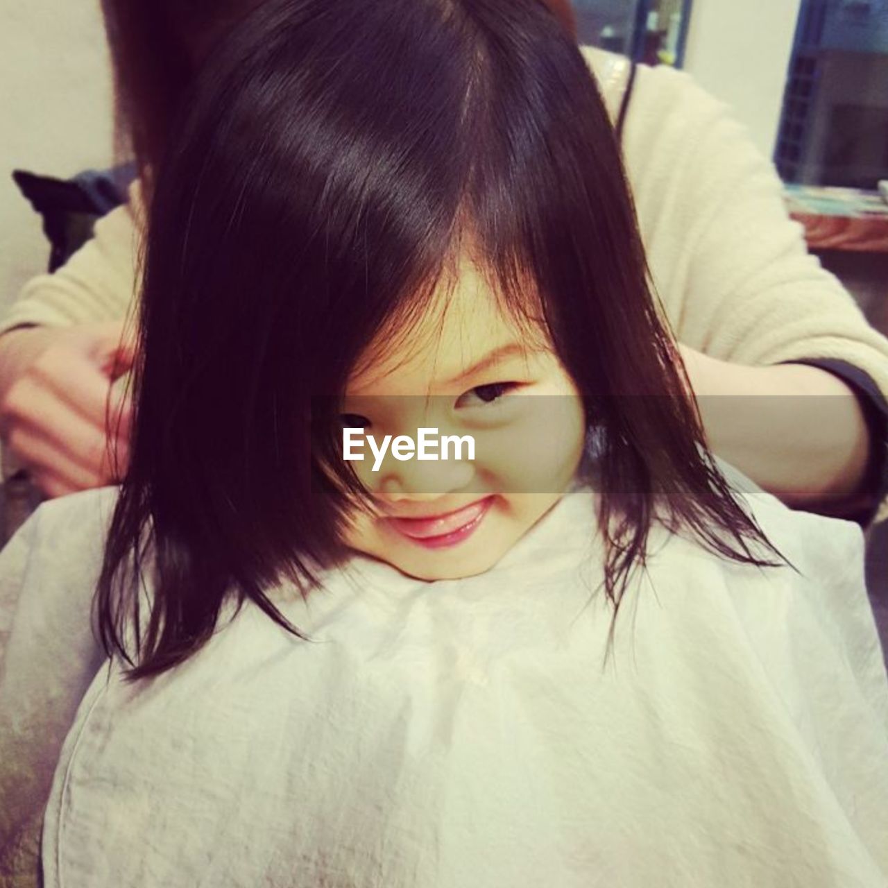 Close-up of cute girl having haircut in salon