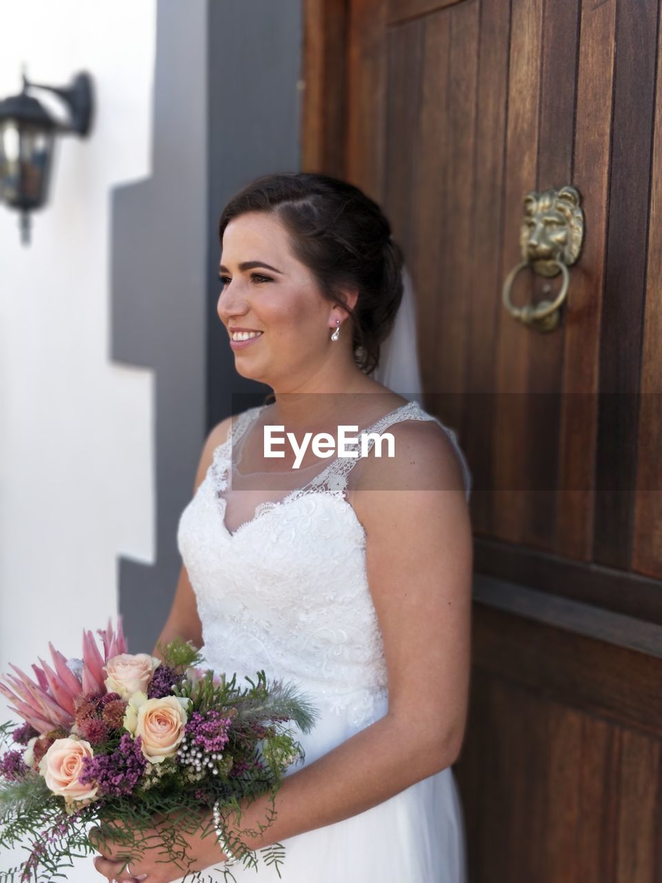 Bride holding bouquet while standing by door