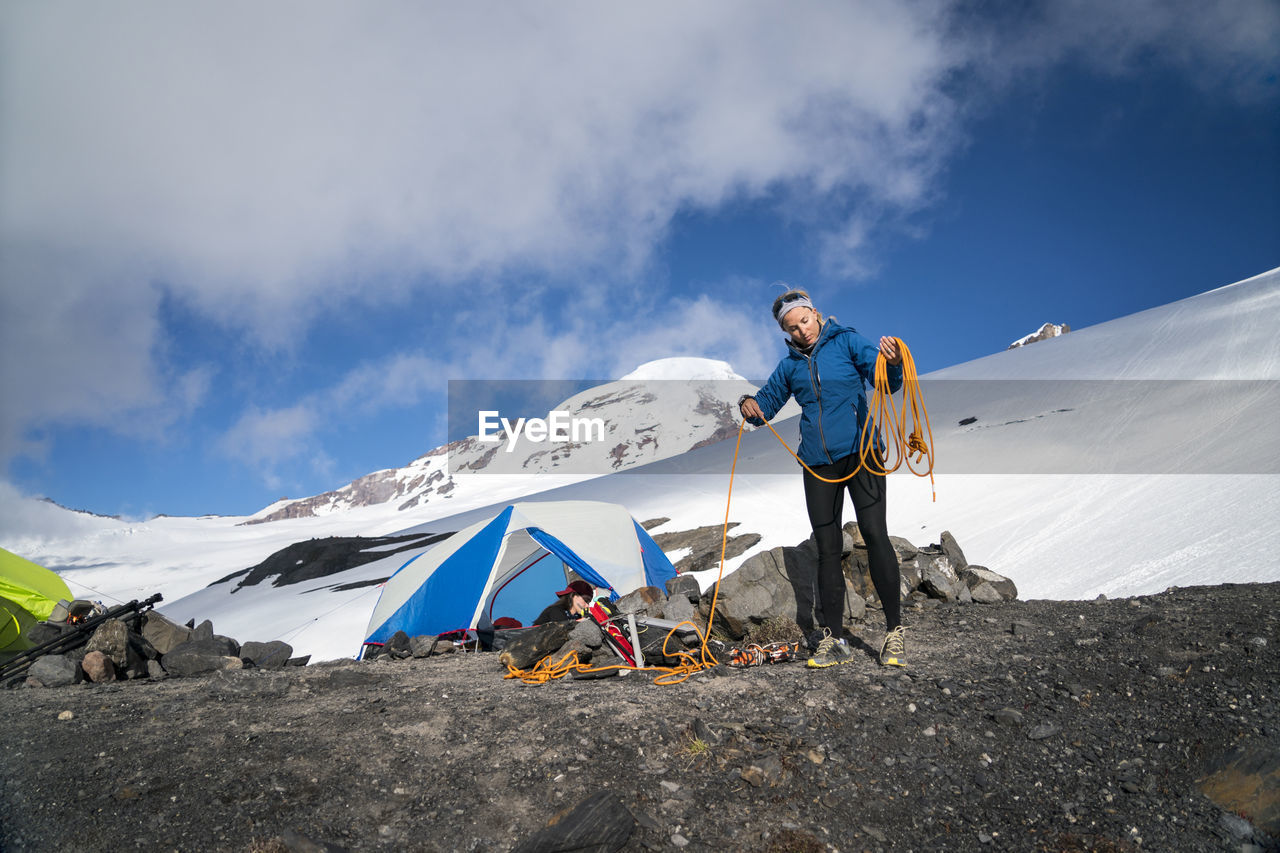 A female mountaineer winds her rope in front of her tent at base camp, mt. baker