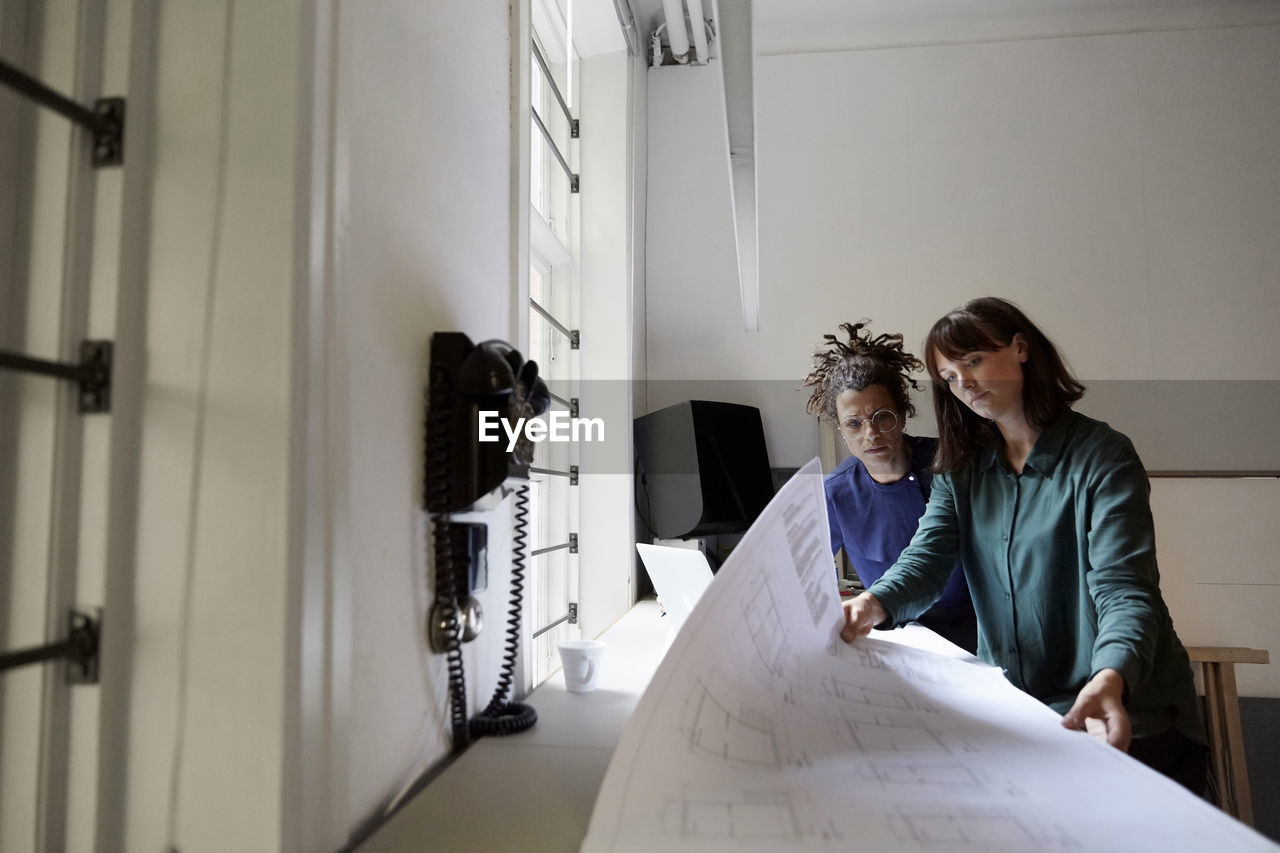 Female architects with blueprint at table in office