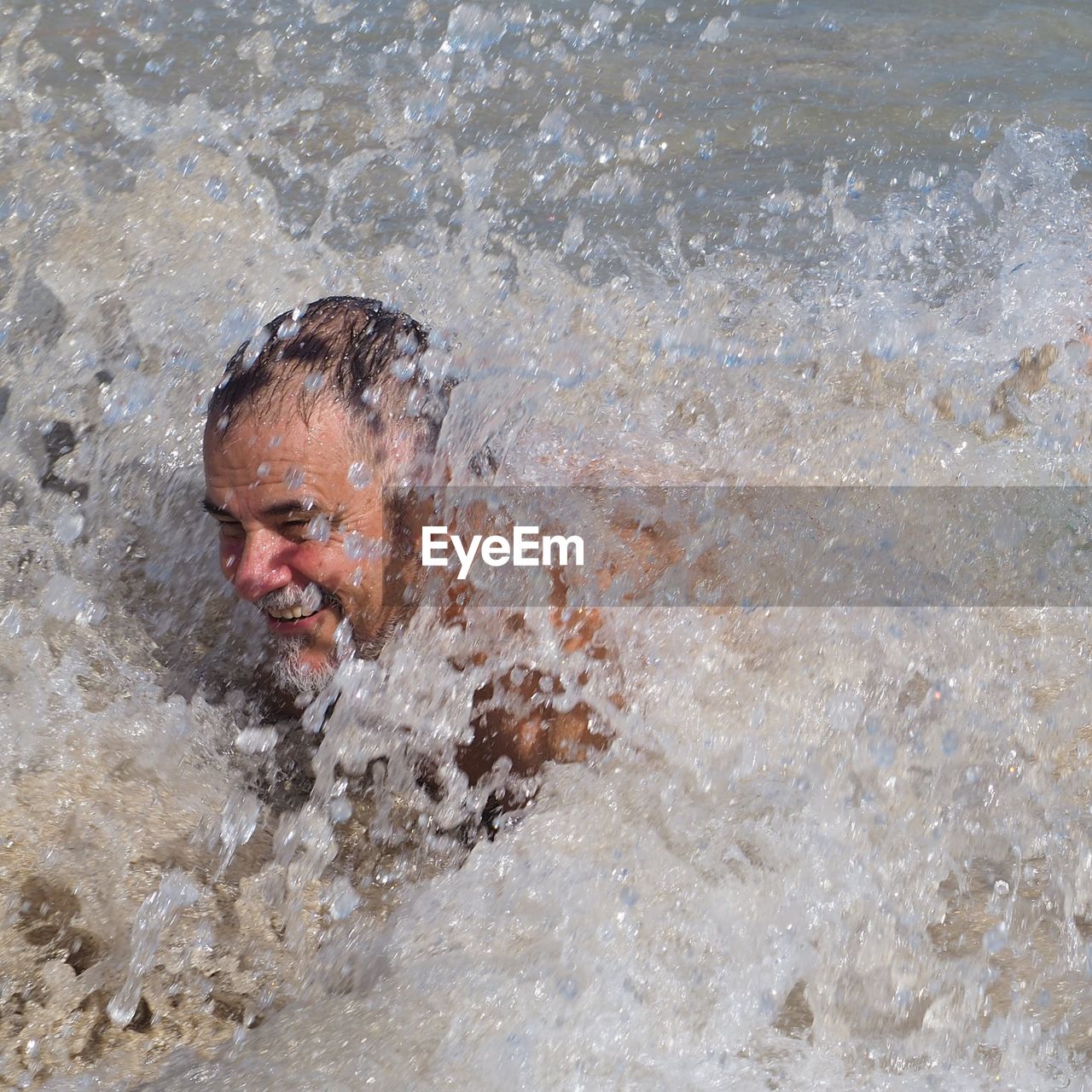 PORTRAIT OF MAN SPLASHING WATER IN WATERFALL