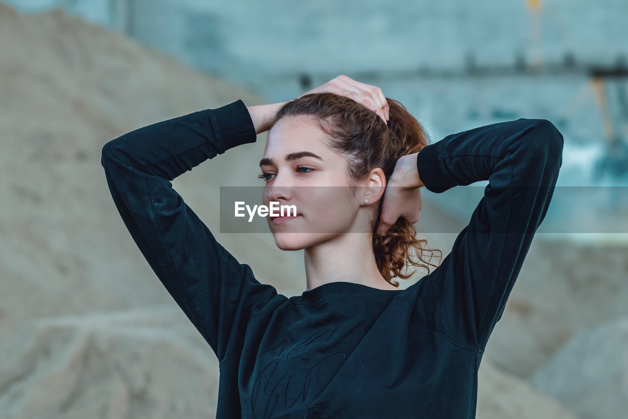 Graceful young woman lifting her hair with both hands