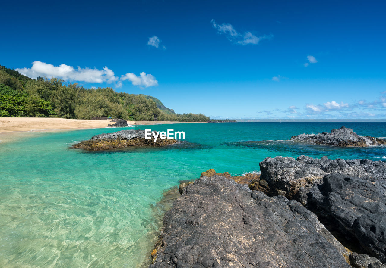 Scenic view of rocks in sea against blue sky