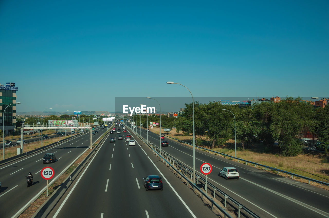 CARS ON HIGHWAY IN CITY AGAINST SKY