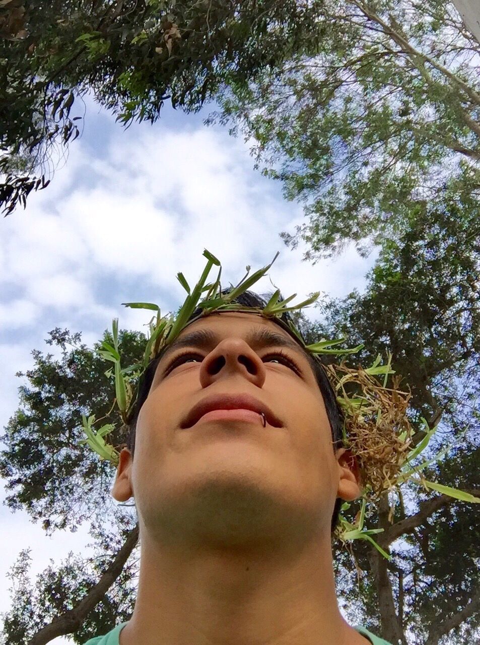 Low angle view of young man wearing grass wreath