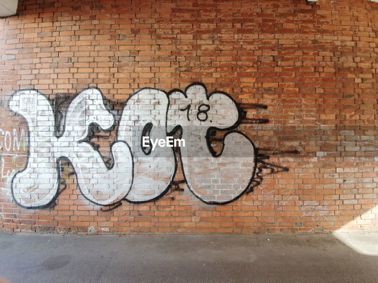 GRAFFITI ON WALL BY BRICK ON FOOTPATH