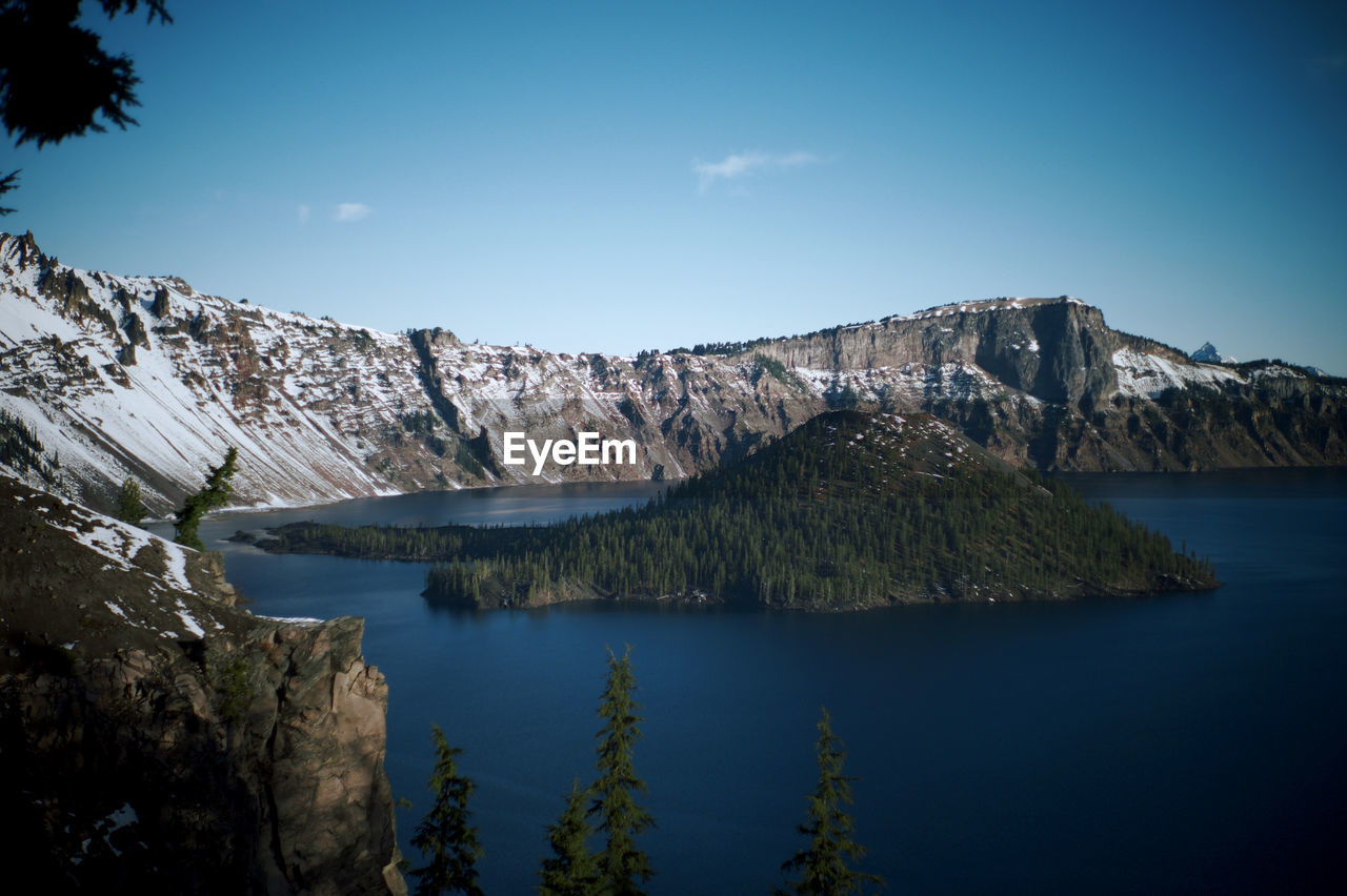 Scenic view of lake and mountains against blue sky