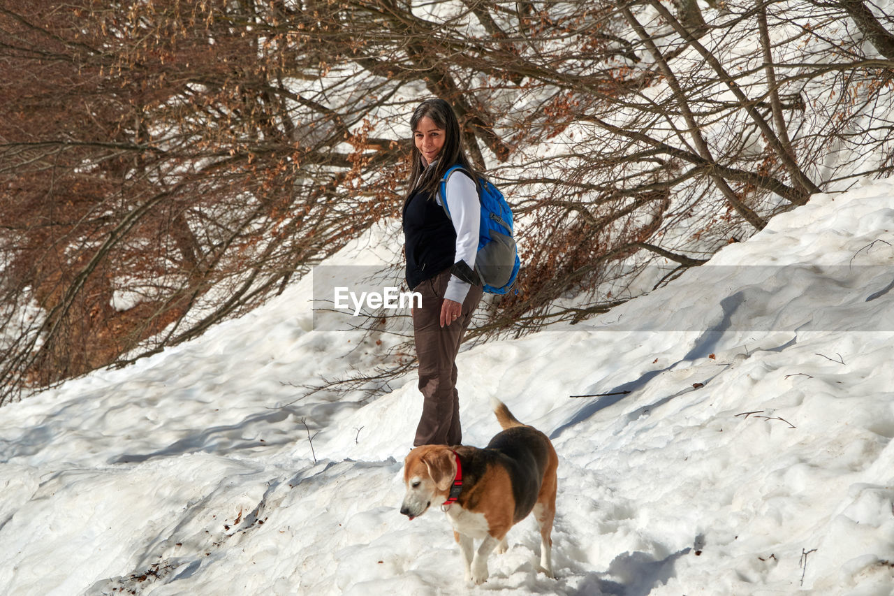 Lady with a beagle dog during a snow hike in the mountains