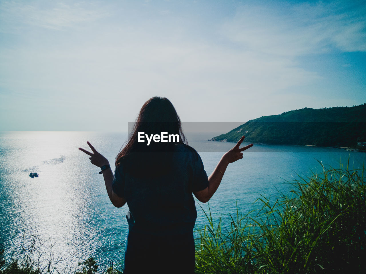 REAR VIEW OF WOMAN STANDING AGAINST SEA