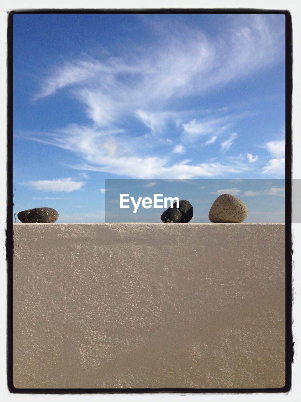 Close-up of stones on wall against clouds