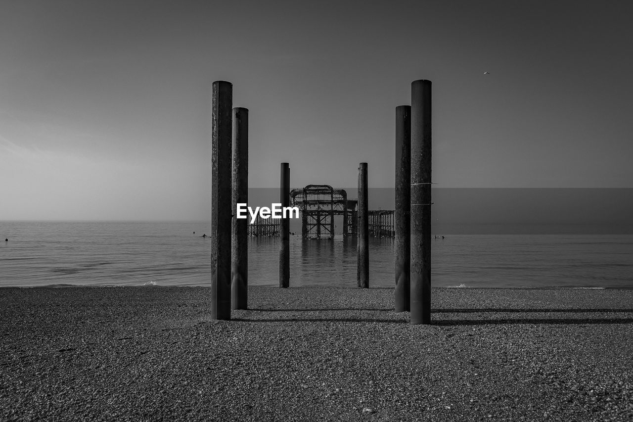 Wooden posts on beach against sky