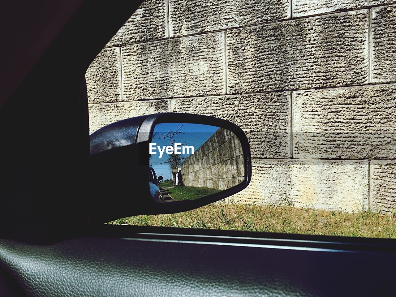 REFLECTION OF MAN ON SIDE-VIEW MIRROR AGAINST CAR WINDOW