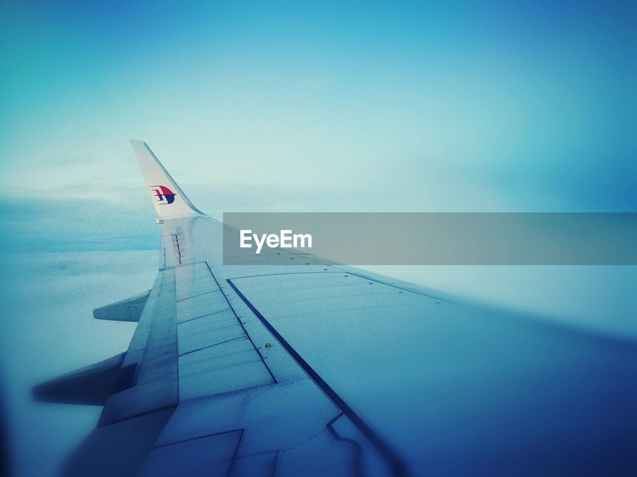 AIRPLANE FLYING OVER SEA AGAINST CLEAR SKY