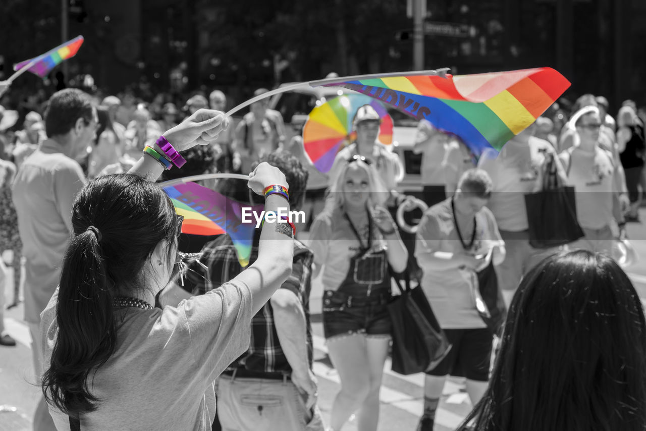 REAR VIEW OF PEOPLE WITH MULTI COLORED UMBRELLAS