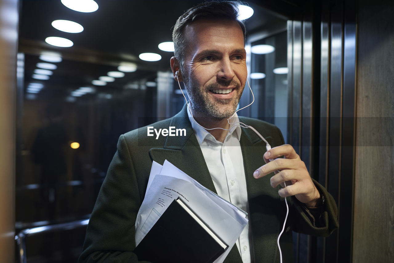 Close-up of businessman talking with headphones while exiting elevator