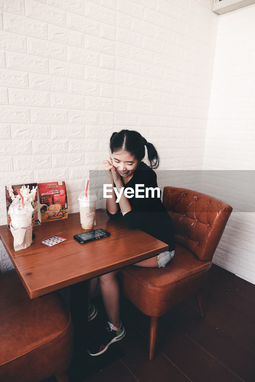 Young woman sitting on table at home