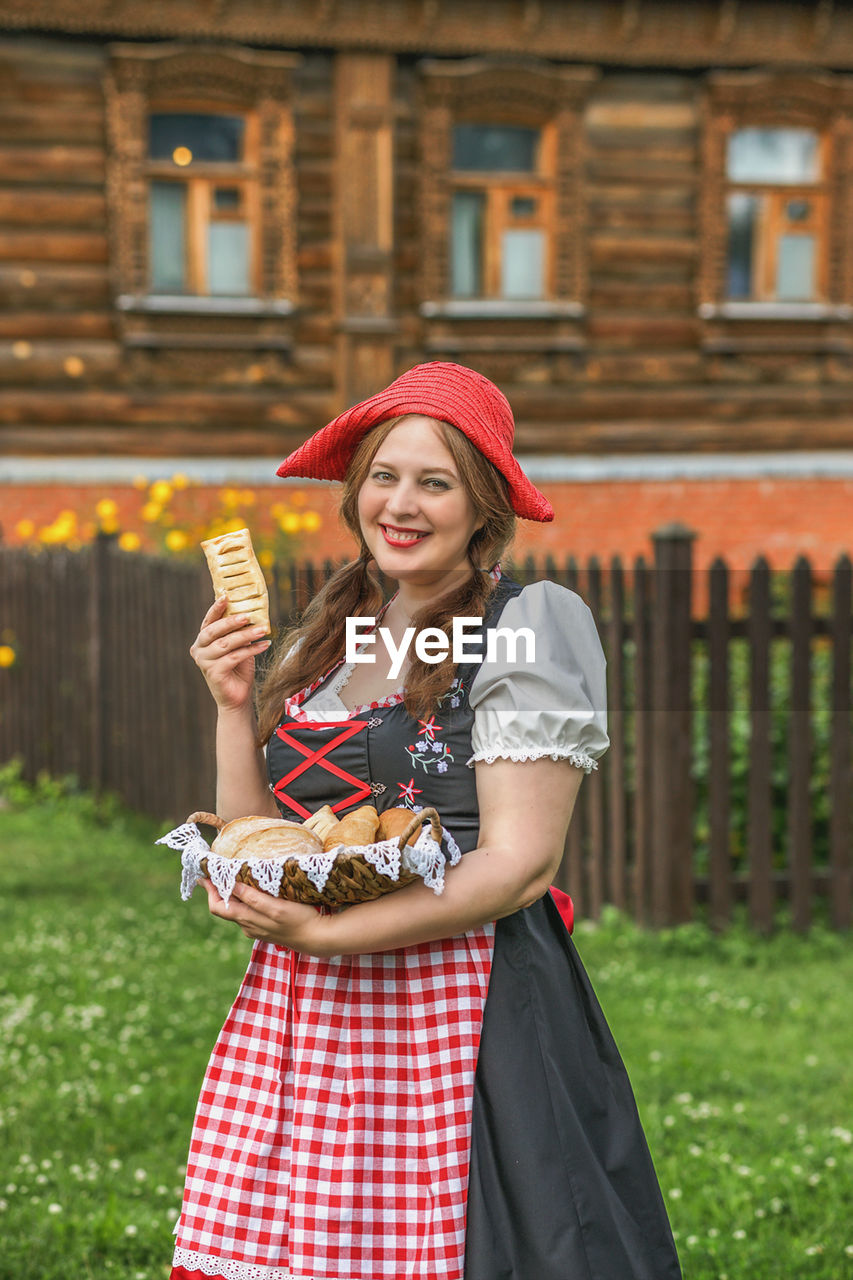 portrait of smiling young woman standing against plants