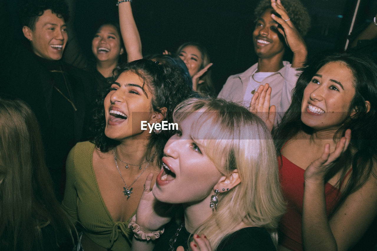 Cheerful multiracial men and women shouting and dancing at nightclub