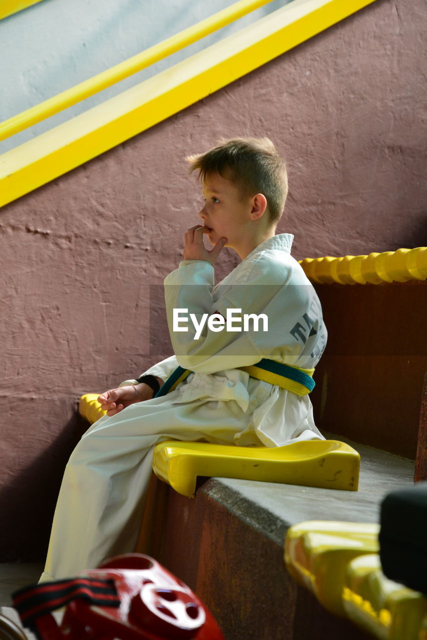 Thoughtful boy in sports clothing sitting on steps