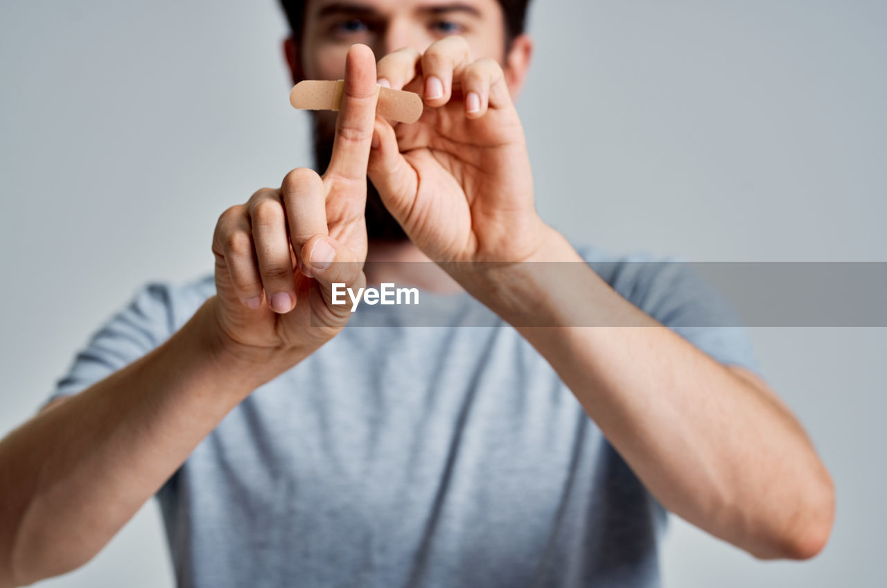 Midsection of man putting bandage on finger