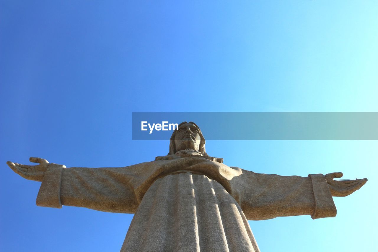 Low angle view of jesus christ statue against blue sky