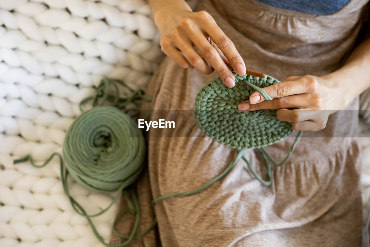 Midsection of woman crocheting at home