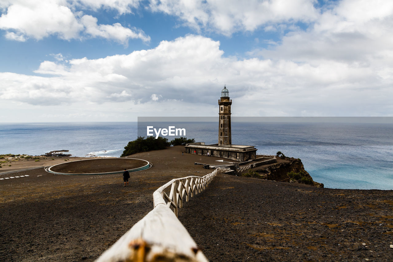 Lighthouse by sea against sky