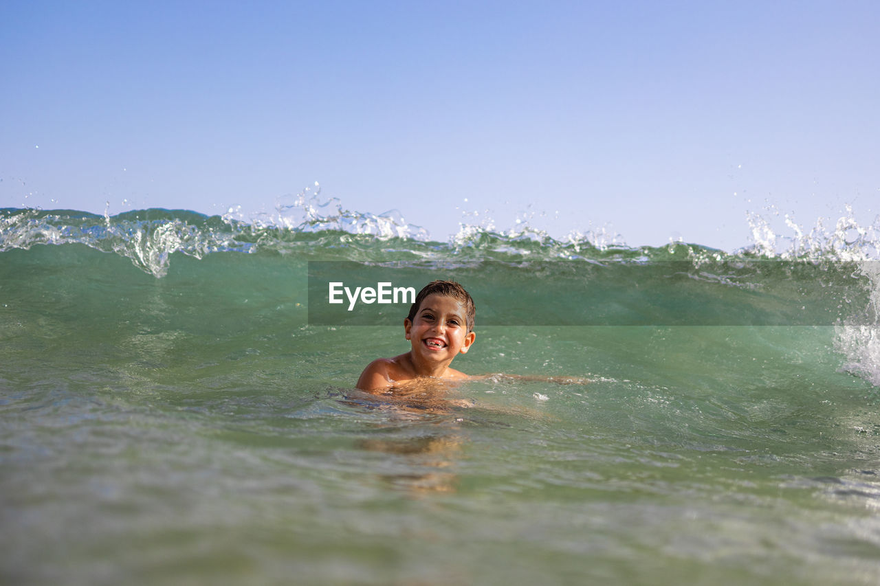 Funny kid playing with waves on the beach