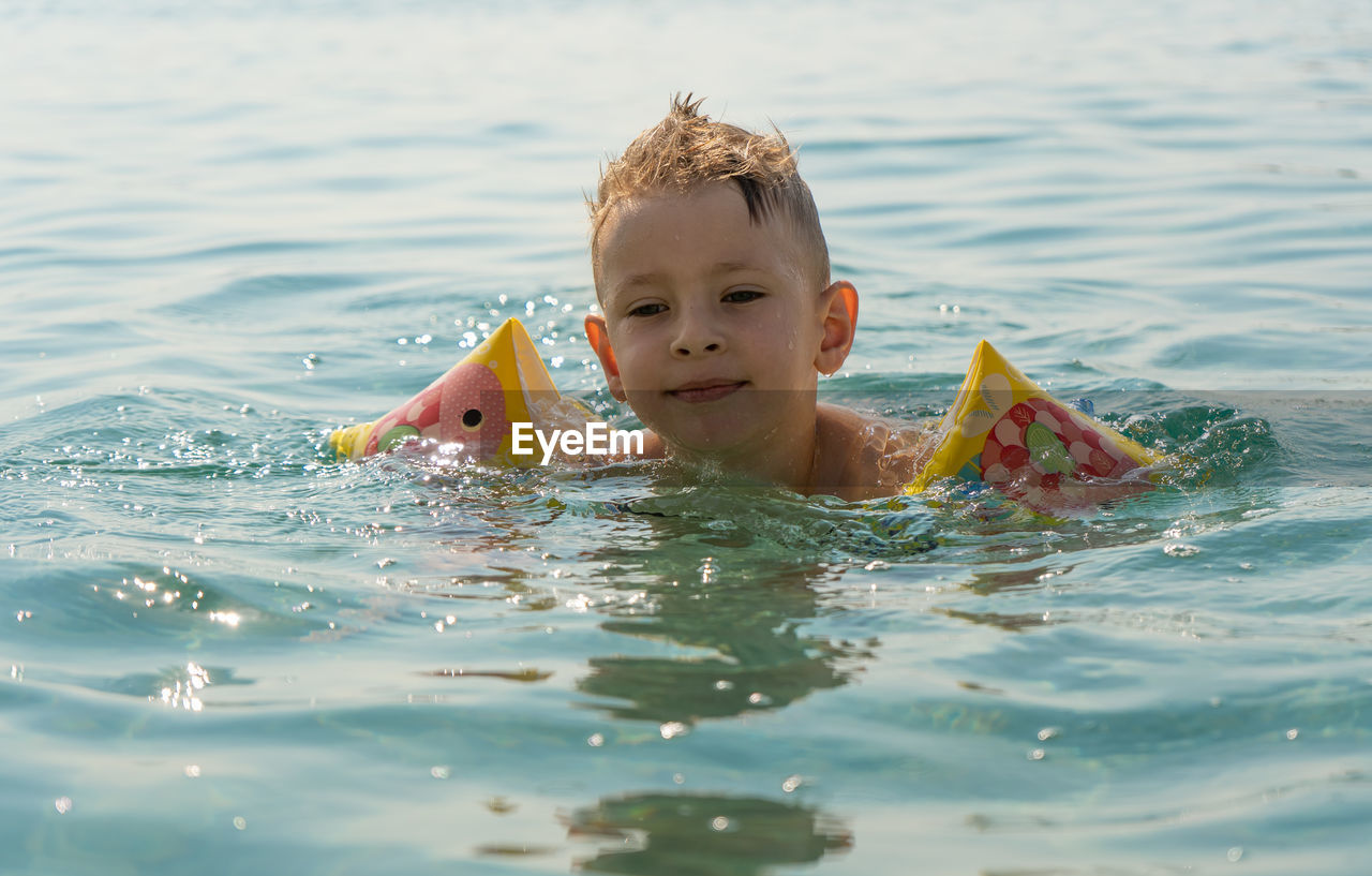 The child learns to swim. happy child swims in the sea. holidays in greece