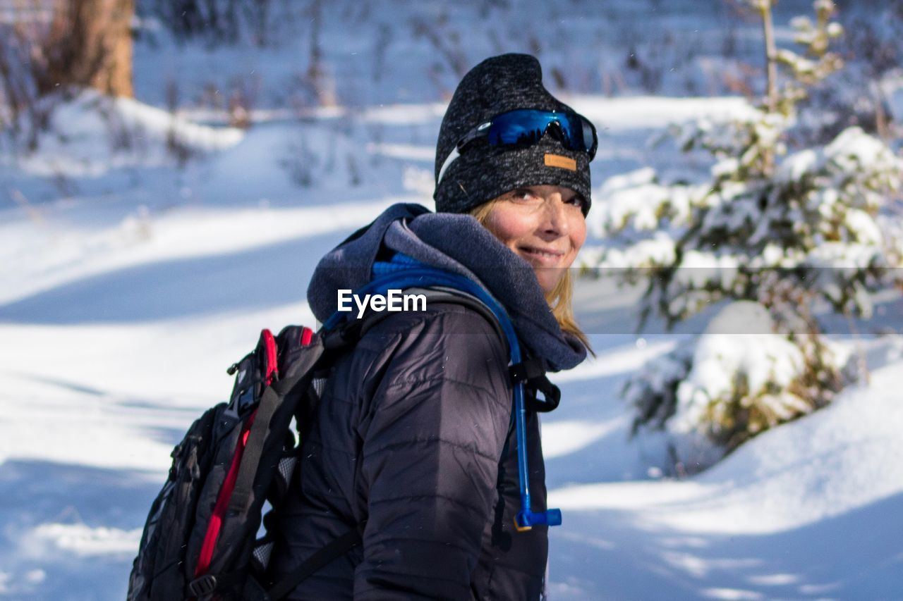 Portrait of mature woman with backpack standing on snow field