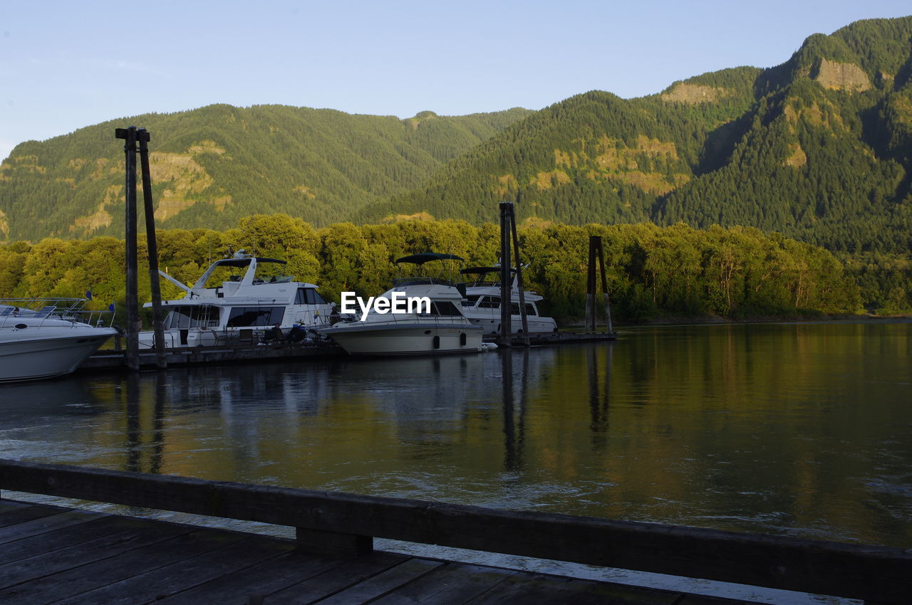 BOATS MOORED BY RIVER AGAINST SKY