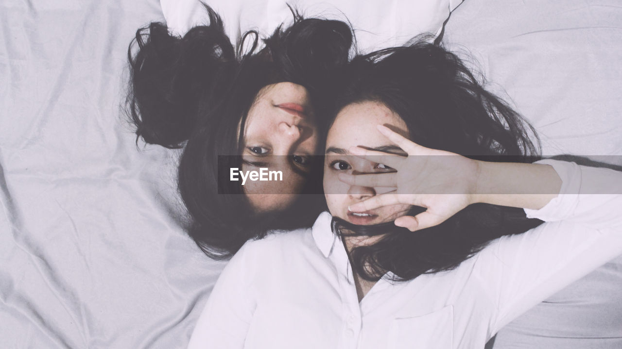 Directly above portrait of twin sisters lying on floor
