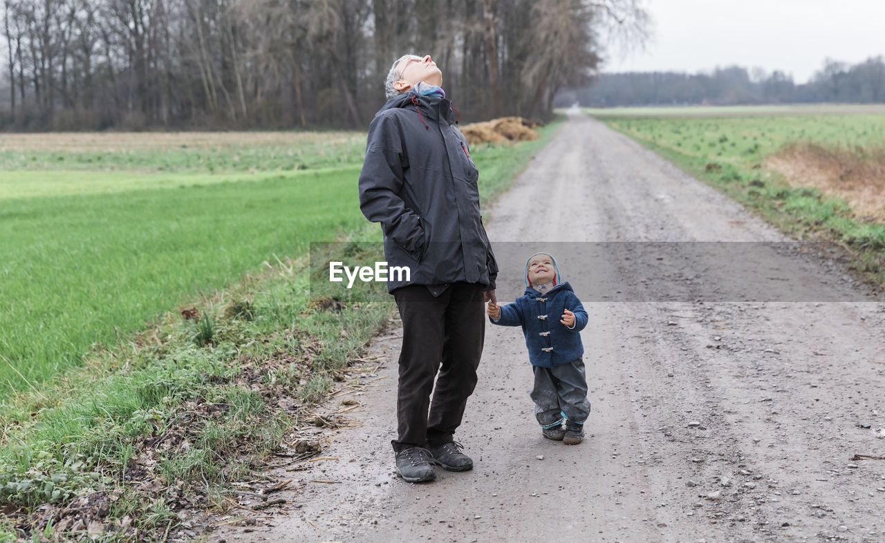 Full length of grandfather with son on dirt road
