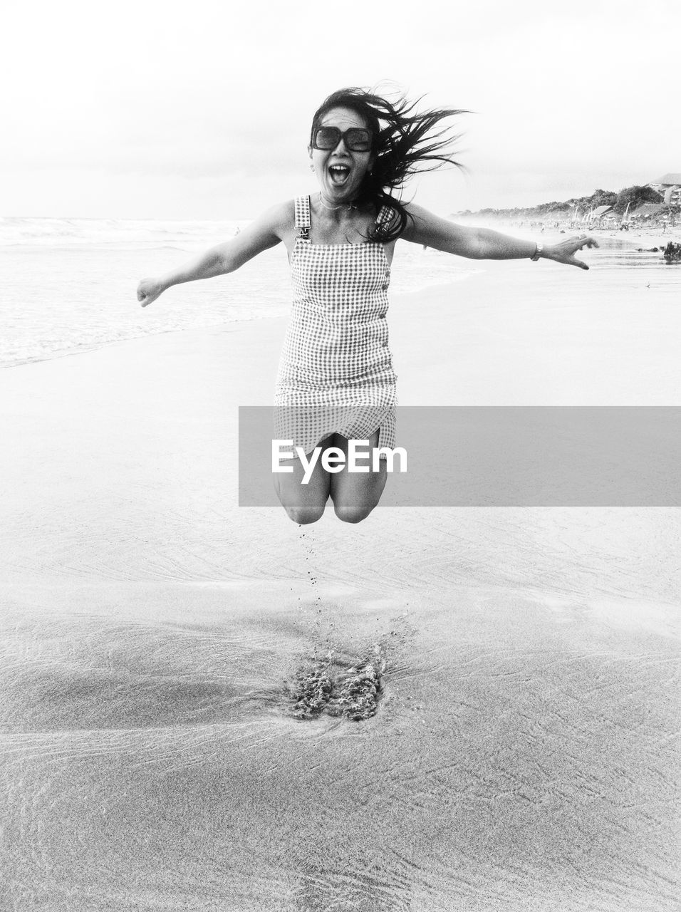 Portrait of young woman jumping on shore at beach