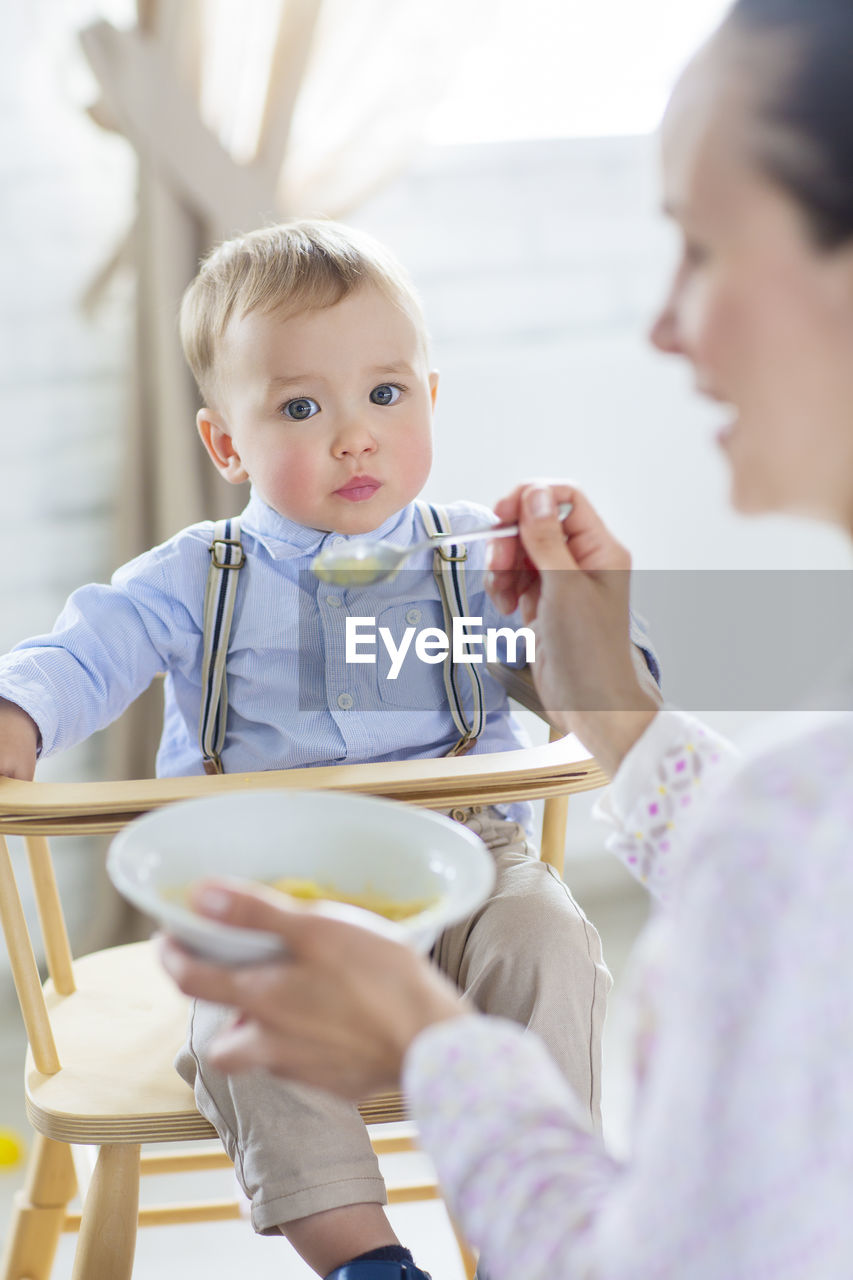 Mother feeding son at home