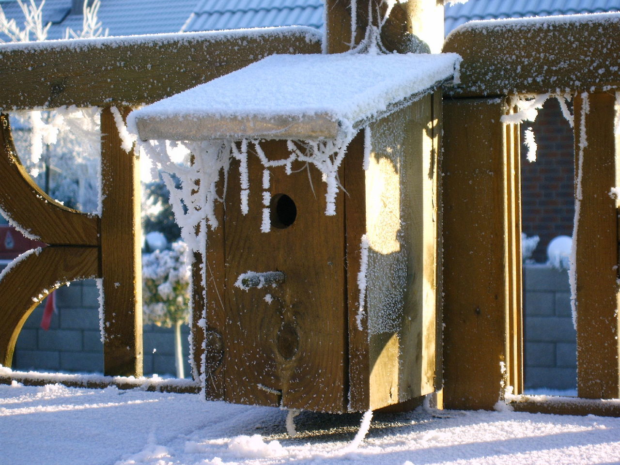 Snow covered birdhouse on fence during winter