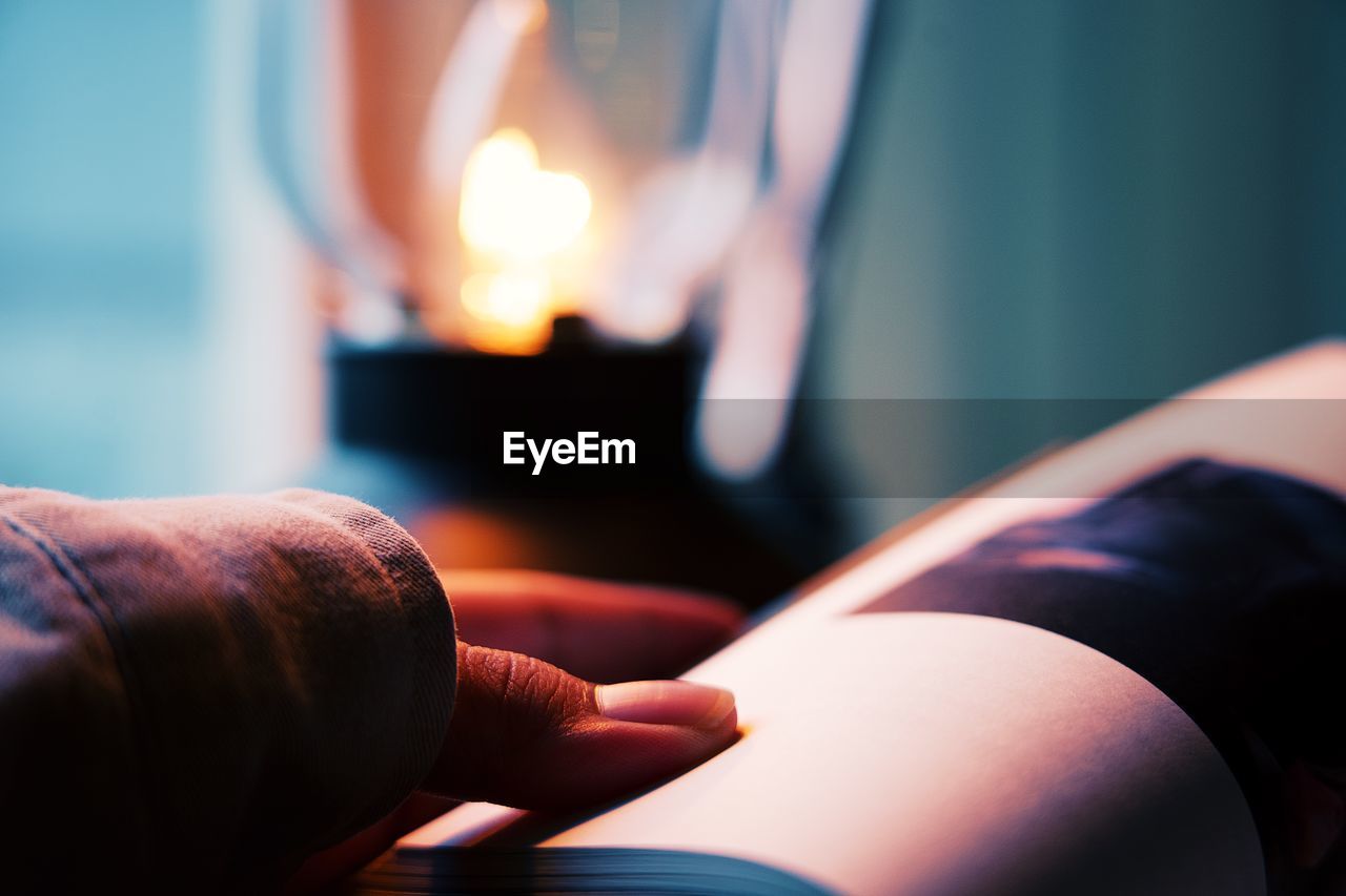 CLOSE-UP OF PERSON HAND HOLDING ILLUMINATED AT HOME