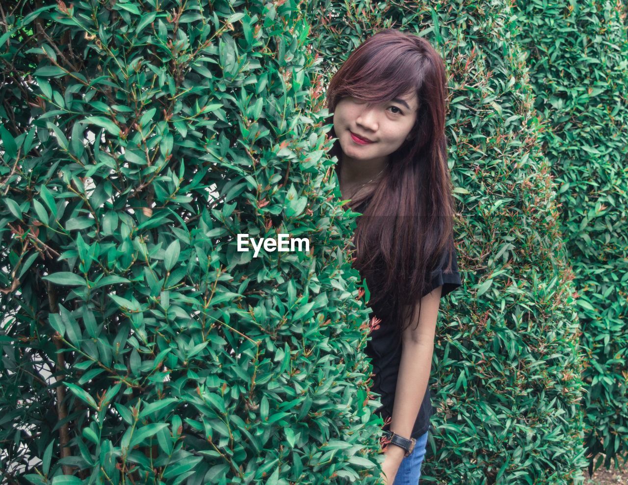 Portrait of woman standing by plants in park