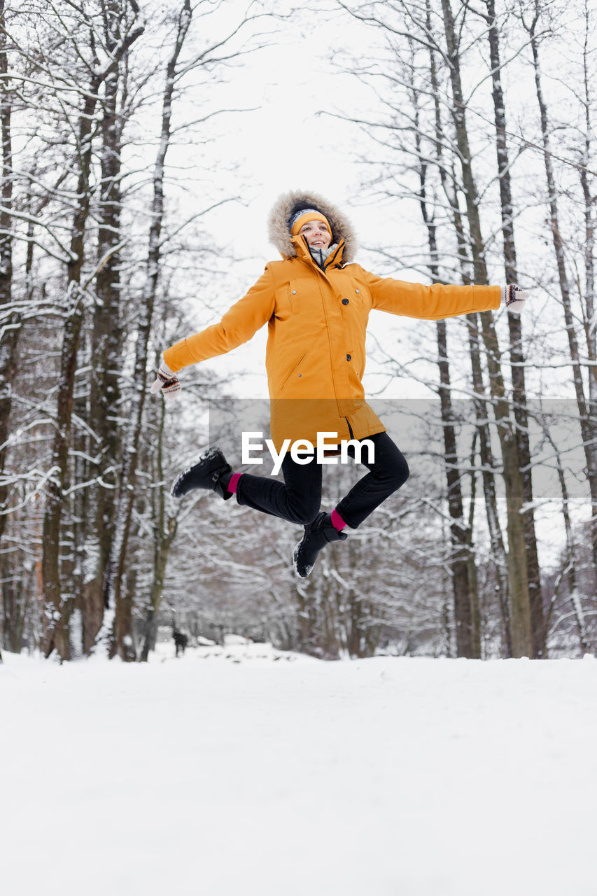 Full length of happy woman with arms outstretched on snow
