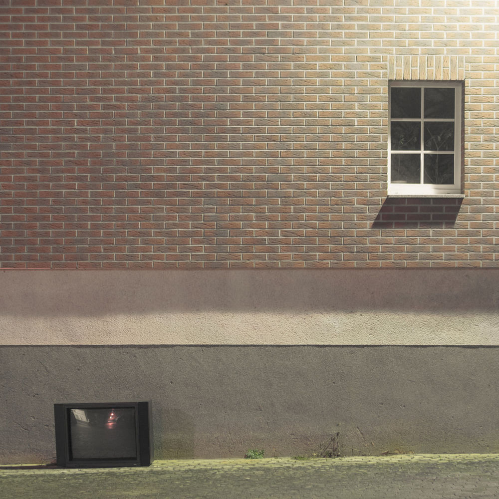 Television on grass against brick wall