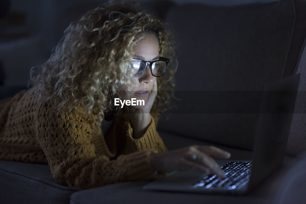 Woman using laptop while working at home in darkroom