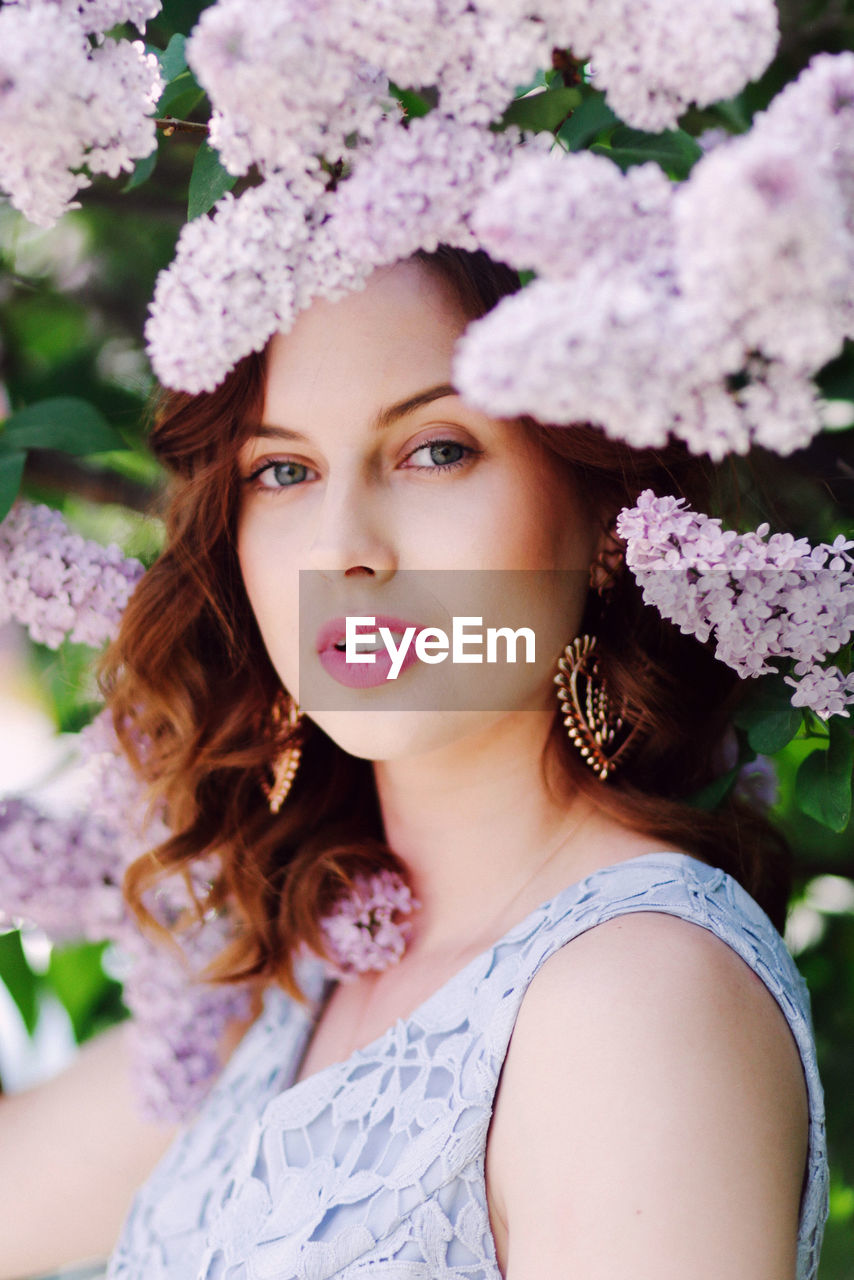 PORTRAIT OF BEAUTIFUL WOMAN WITH PINK FLOWER IN SUNLIGHT